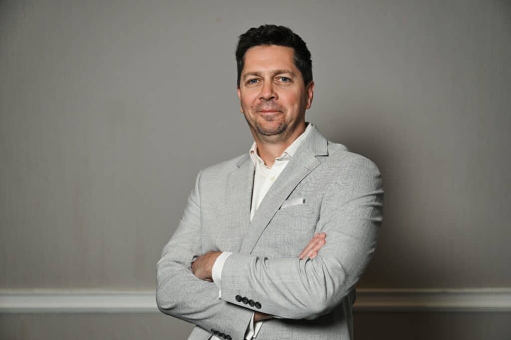 Ben Sherriff, Business Development Director of ENSE, smiling in a professional headshot wearing a light grey suit jacket and white shirt.