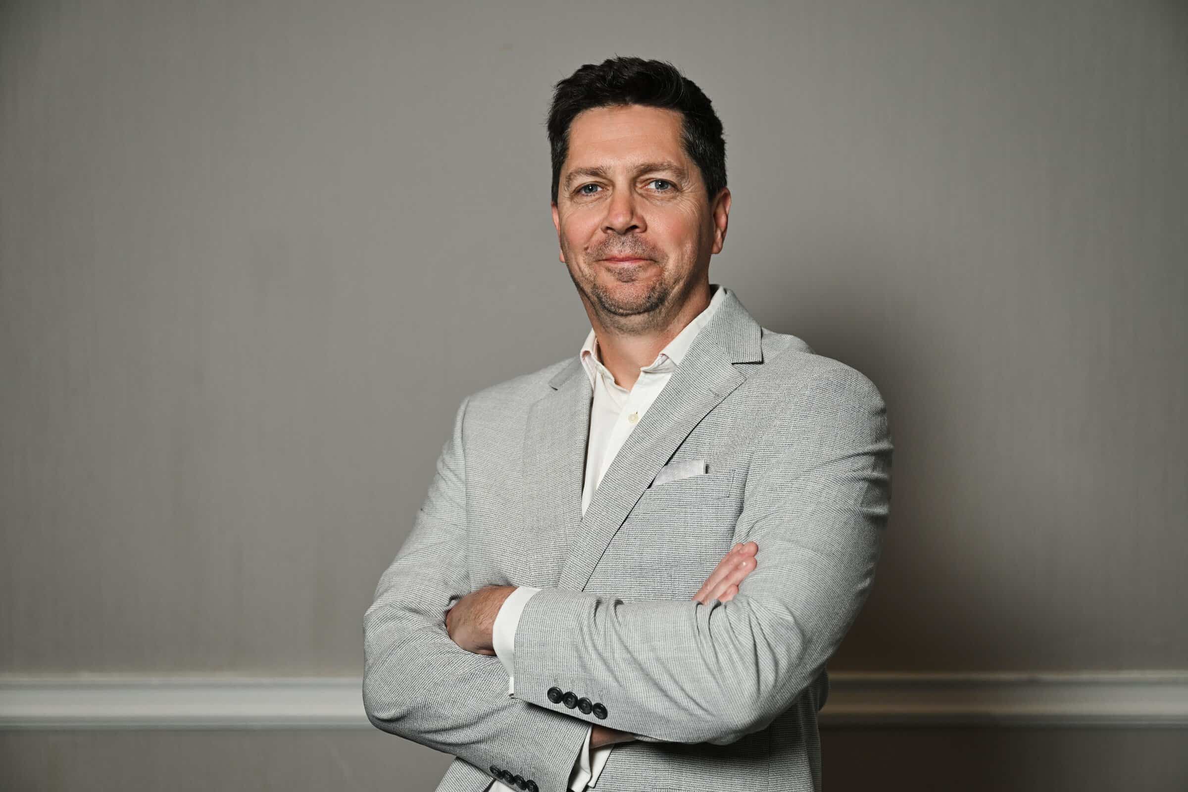 Ben Sherriff, Business Development Director of ENSE, smiling in a professional headshot wearing a light grey suit jacket and white shirt.