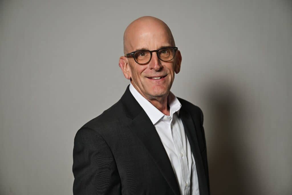 Bob Adams, Managing Director of ENSE, smiling in a professional headshot wearing a dark grey suit jacket and white shirt.