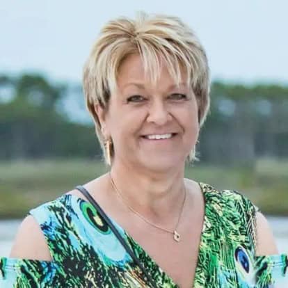 Marilyn Smith, Accounts Manager for ENSE, smiling in a professional headshot wearing a green dress.