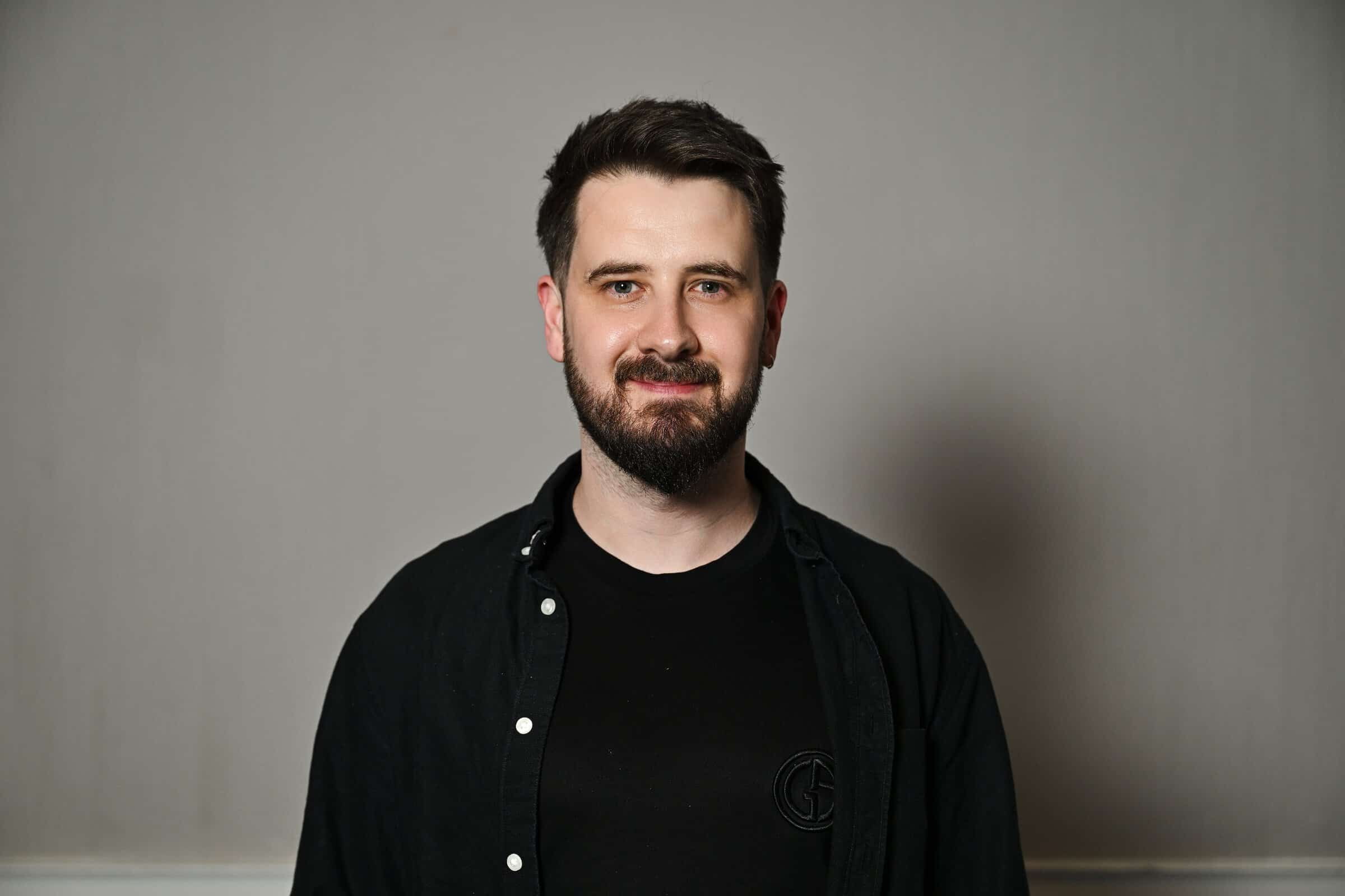 Neil Robertson, Marketing Consultant for ENSE, smiling in a professional headshot wearing a black t-shirt underneath a black shirt.